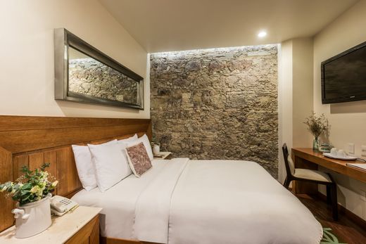 Cozy hotel room with a neatly made bed, stone accent wall, and desk with lamp and decor