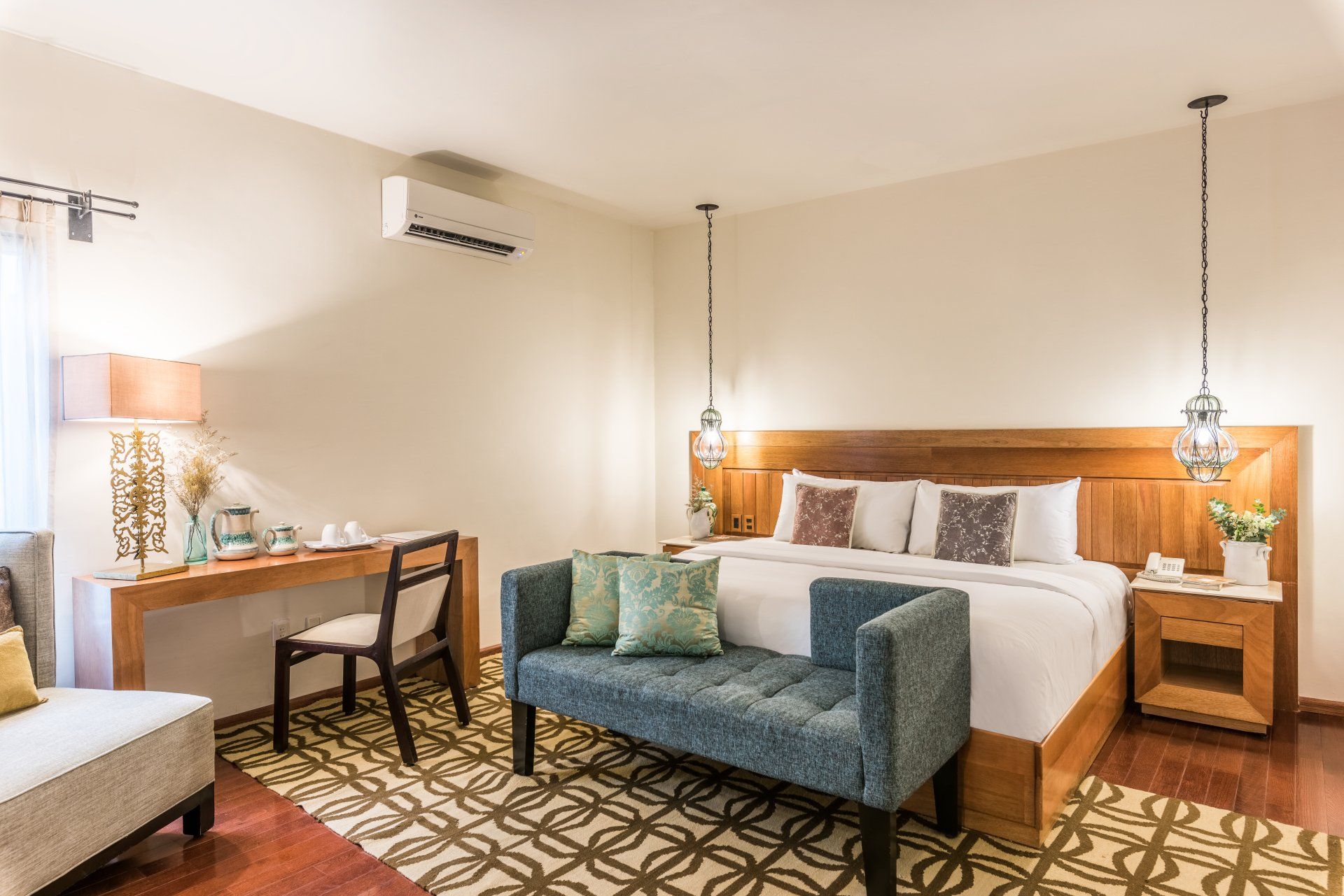 Modern hotel room with a king bed, desk, sofa, and warm lighting