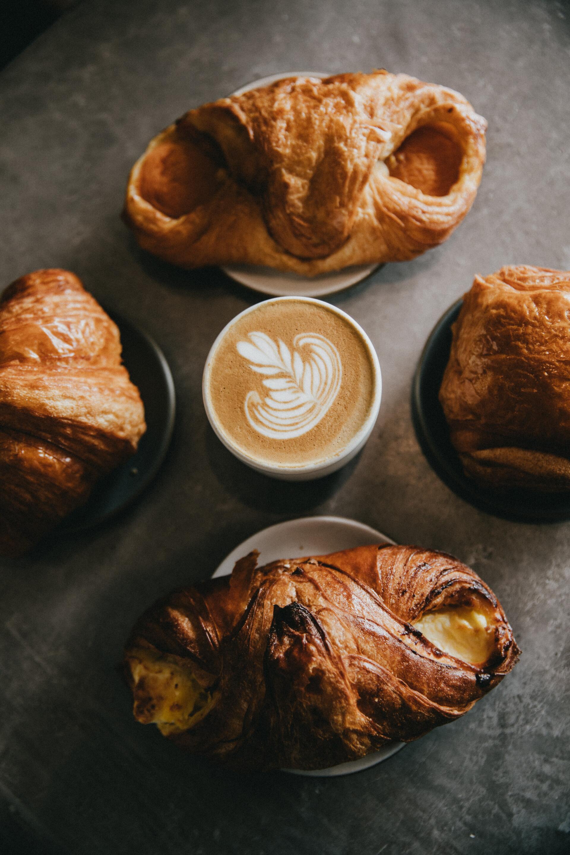 Croissants and a latte with latte art on a dark table, viewed from above