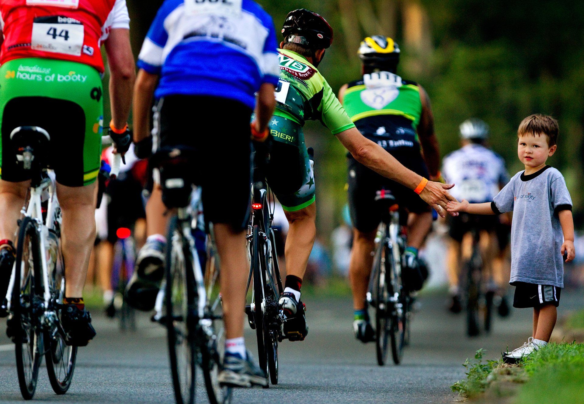 a boy gives high-fives to riders in a charity benefit cycling event