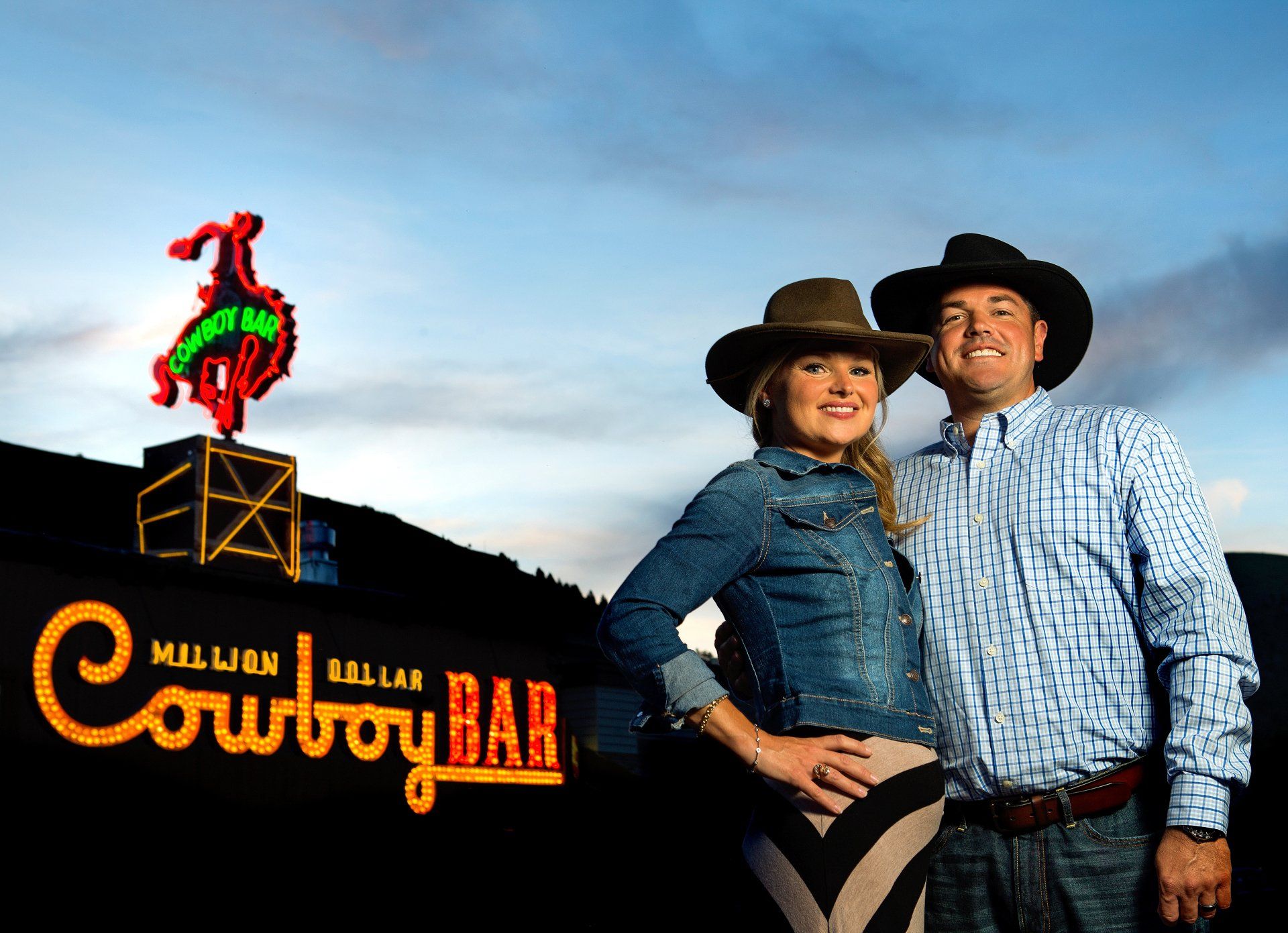 A man and woman in western wear outside a cowboy bar