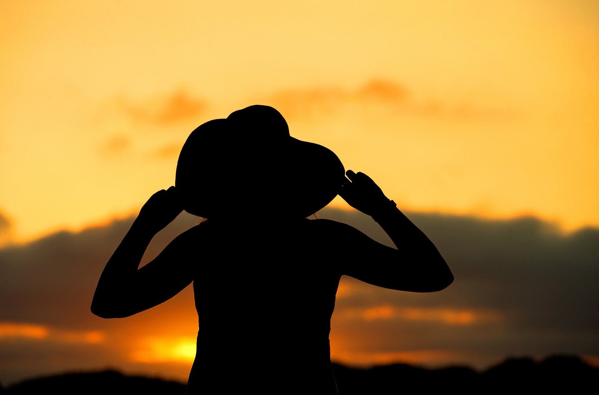 A woman in a sun hat at sunset