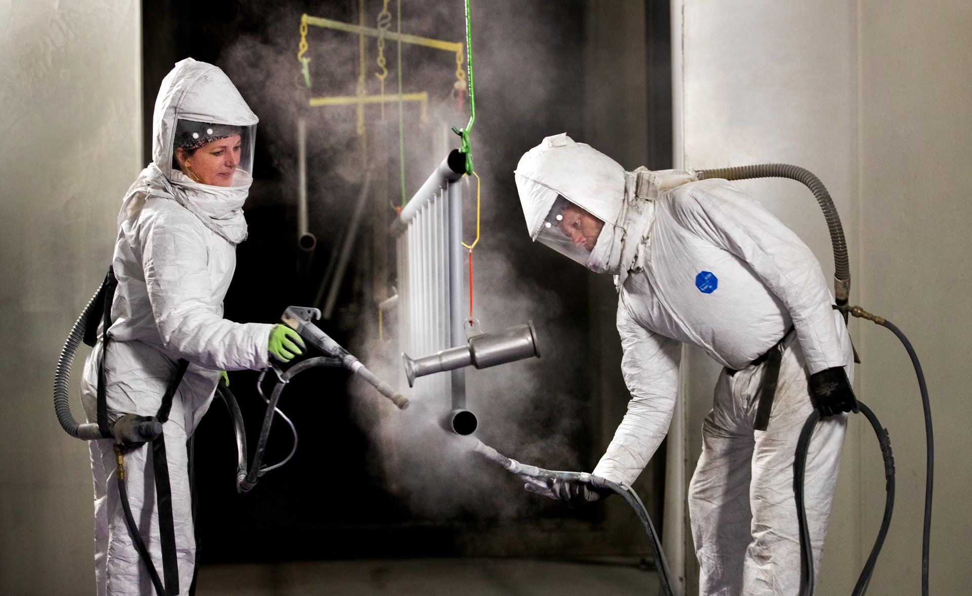 man and woman wearing safety suits while spraying in a facility