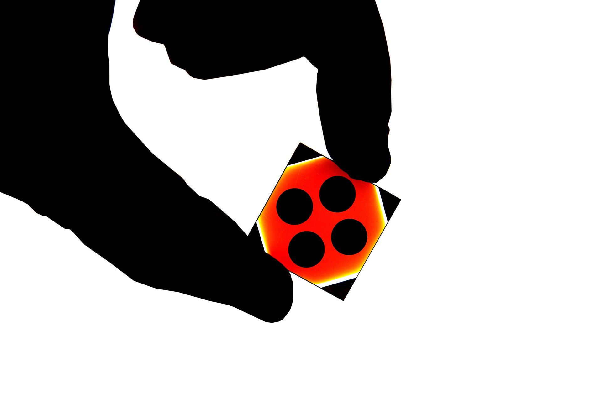 close-up of tech chip being held by a silhouetted thumb and forefinger.