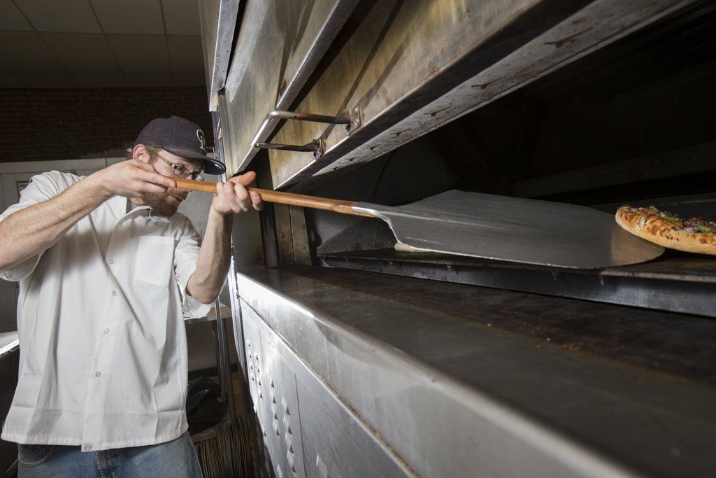Pizza chef checking the pizza in the oven