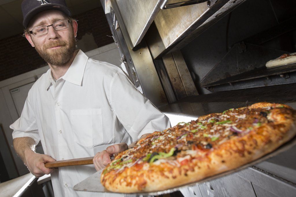 Pizza chef taking pizza out of the oven