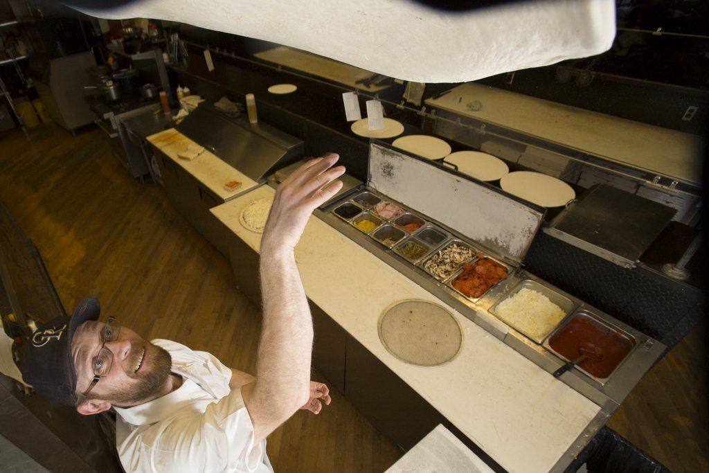 a pizza chef spinning dough in the air