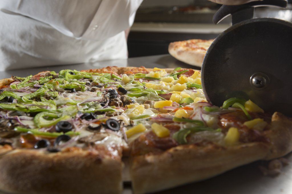Fresh baked pizza getting cut