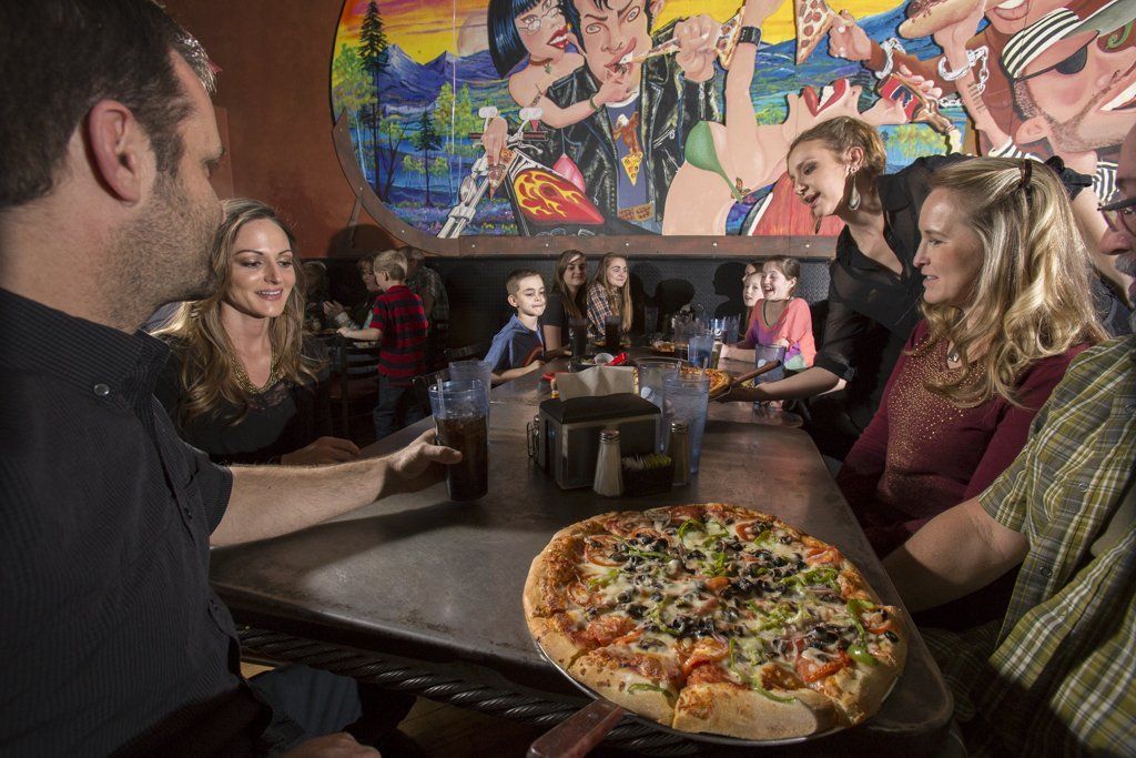 Family and friends at table with pizza