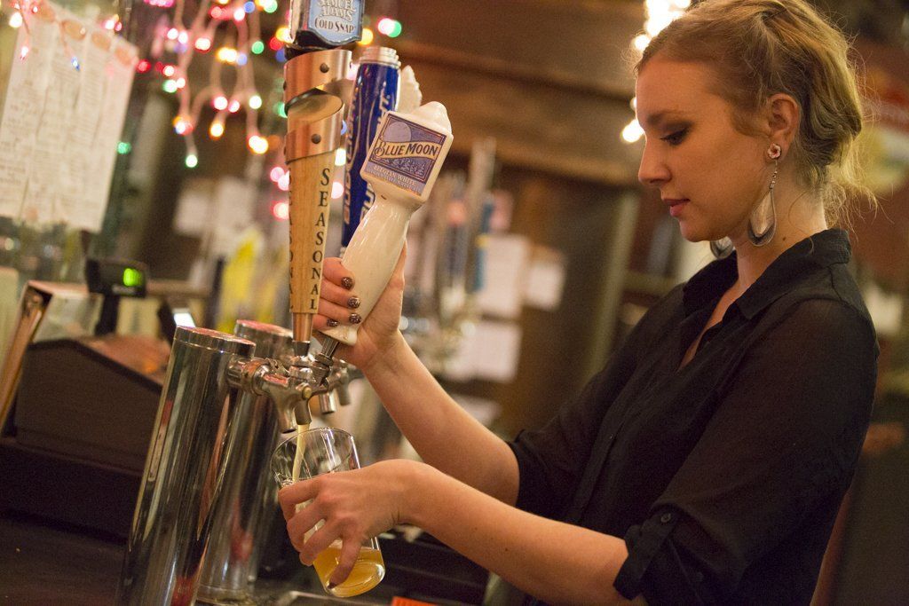 Waitress getting drinks from the bar for pizza madness guests