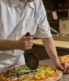 pizza chef at pizza madness cutting a fresh pizza