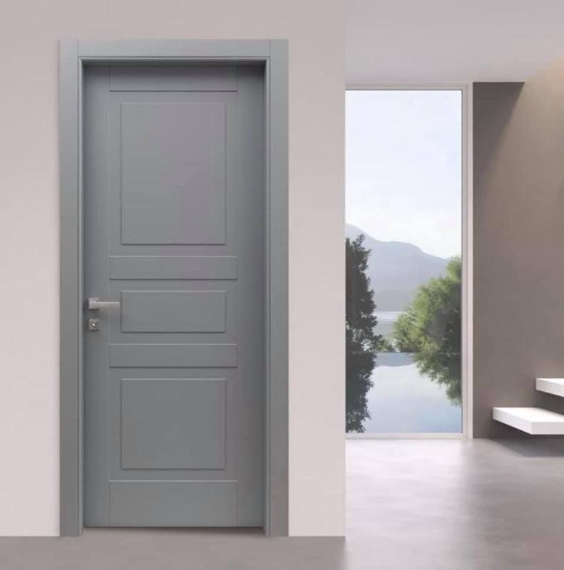 Porta interna grigia con pannelli e maniglia argentata, vicino a una finestra con vista sulle montagne e sull'acqua.