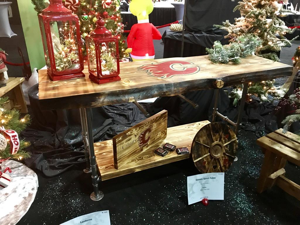 Rustic holiday display with red lanterns, wooden shelves, greenery, and decorative wagon wheels