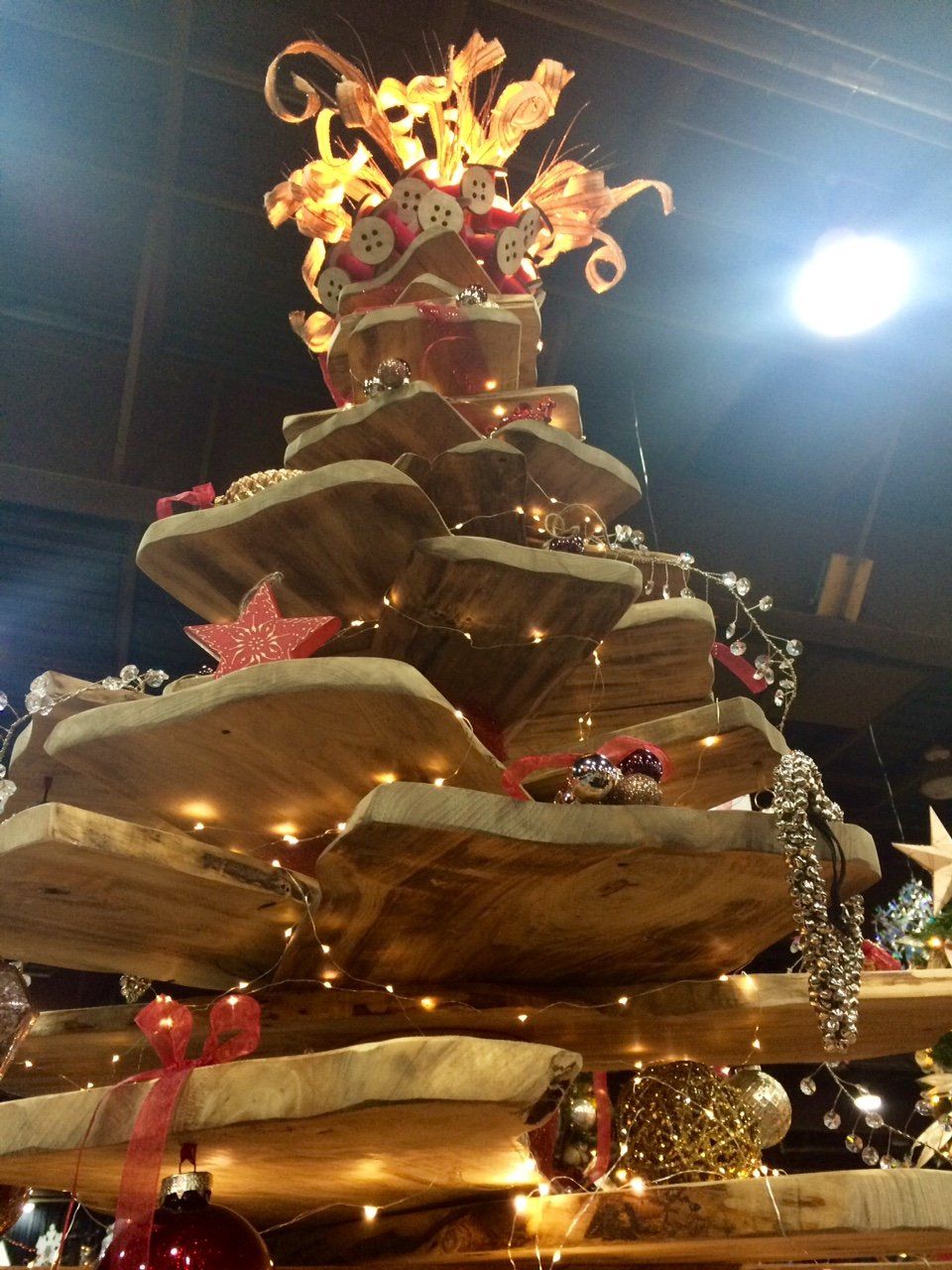 Tall Christmas tree sculpture with glowing ribbon-like tiers and lights indoors at night