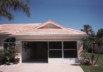 Single-story house with a peach roof, white garage door, and a driveway under a clear blue sky