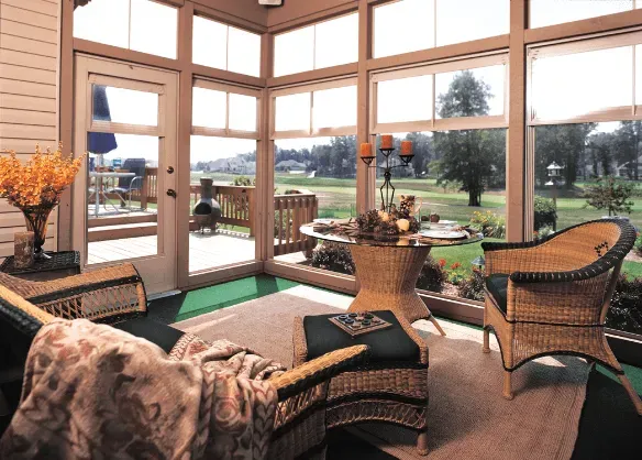 Inside Dim Sunrooms — Springdale, AR — Backyard Designs Inc. Sunroom with wicker chairs, floral decor, and a view of a green lawn and trees through large windows