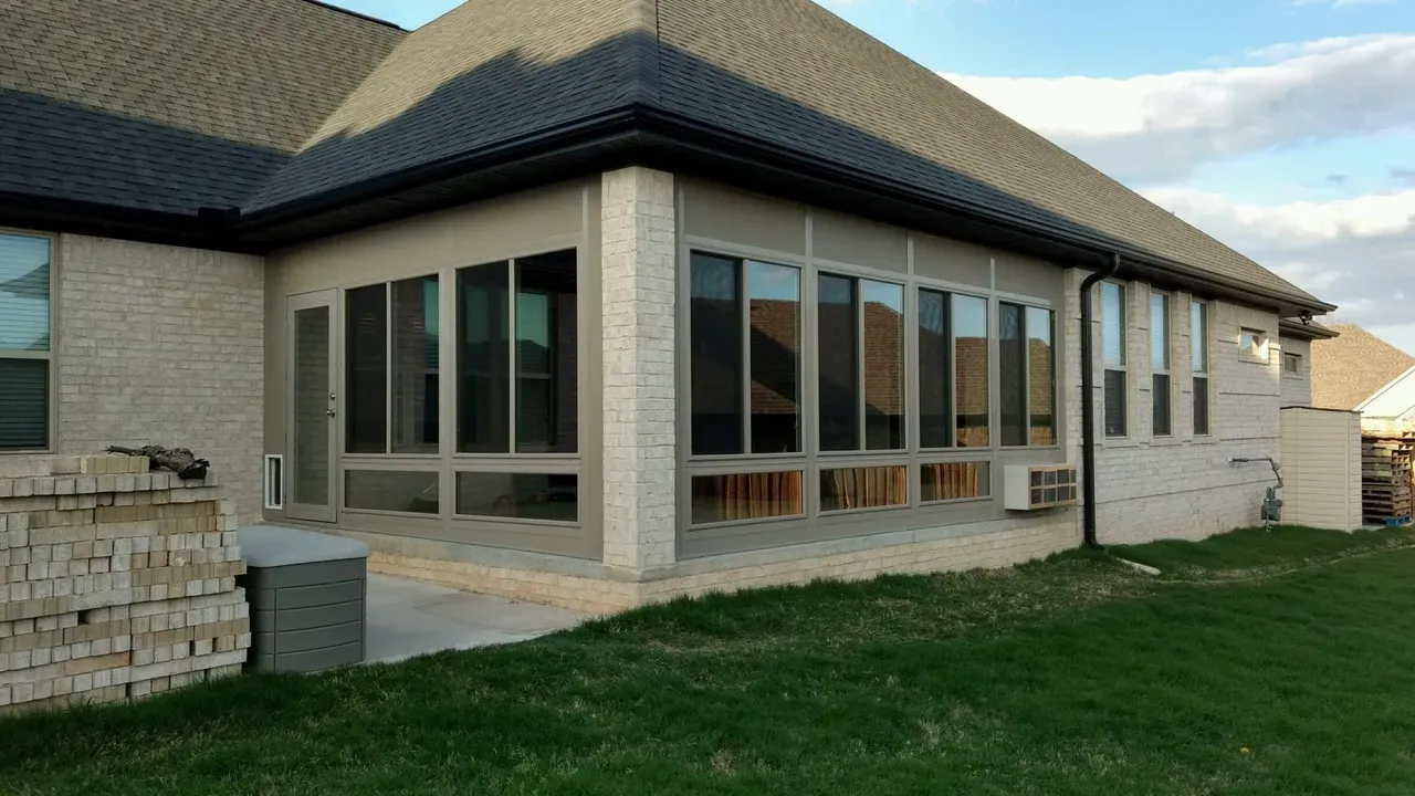 Modern brick house with a dark roof, large windows, and a grassy front yard