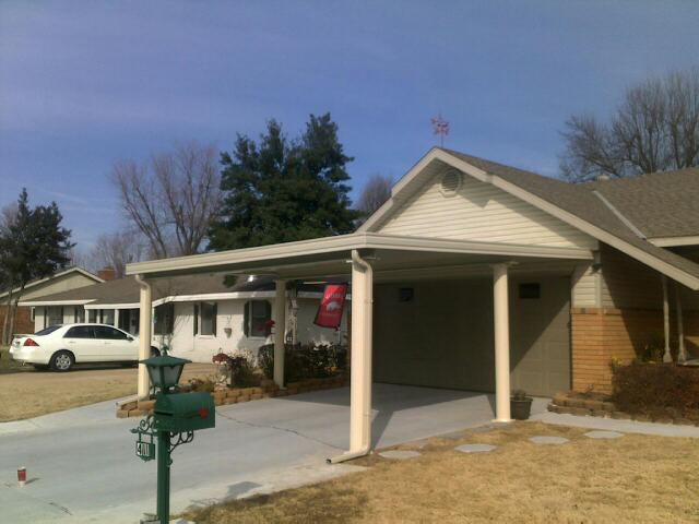 Suburban house with a carport, driveway, and parked white car on a sunny day