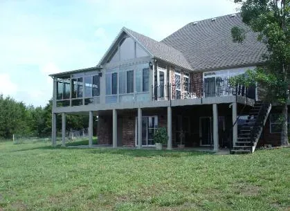 Elevated house with wraparound deck and outdoor staircase in a grassy yard