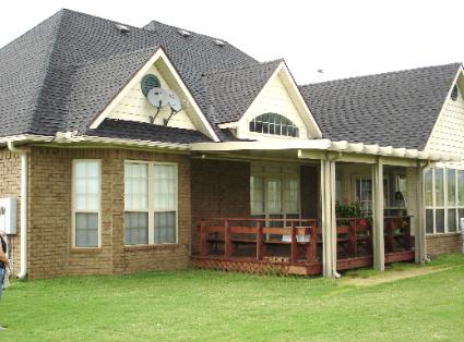 Brick house with a covered porch, white trim, and satellite dish on a green lawn