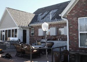 Patio seating in front of a brick house with white-trimmed windows and a lamp post