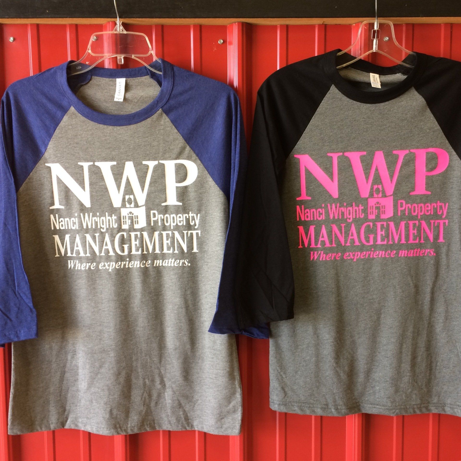 Two baseball-style t-shirts hanging, one blue/gray, one black/gray, each with
