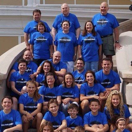 Large group wearing blue shirts pose on outdoor steps.