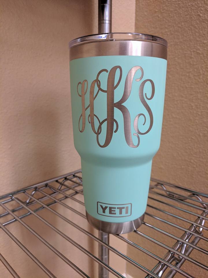 Aqua Yeti tumbler with silver monogram HKS on a wire shelf.