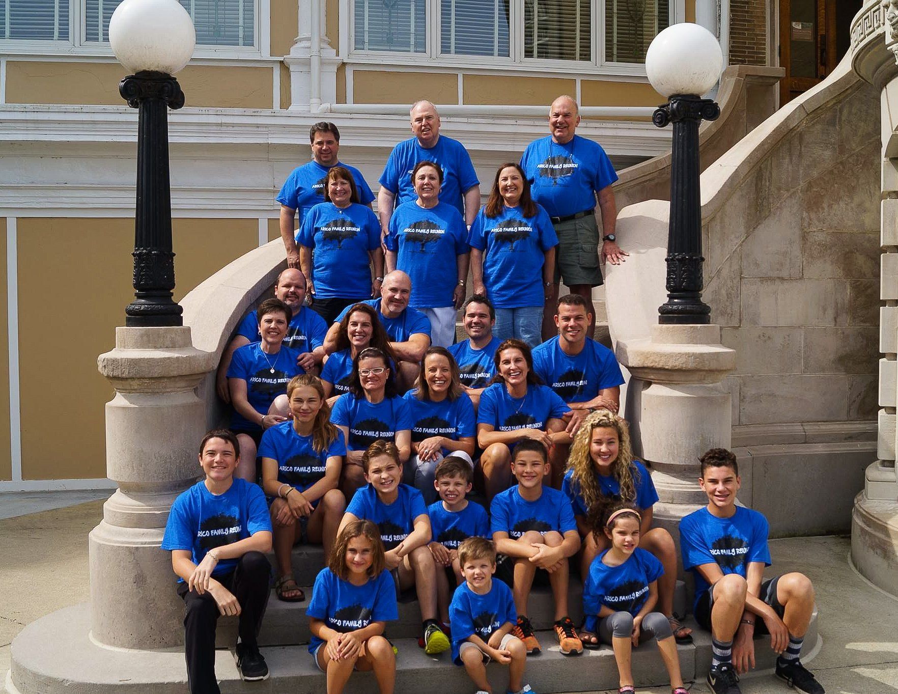 Group of people in blue shirts pose on outdoor steps.