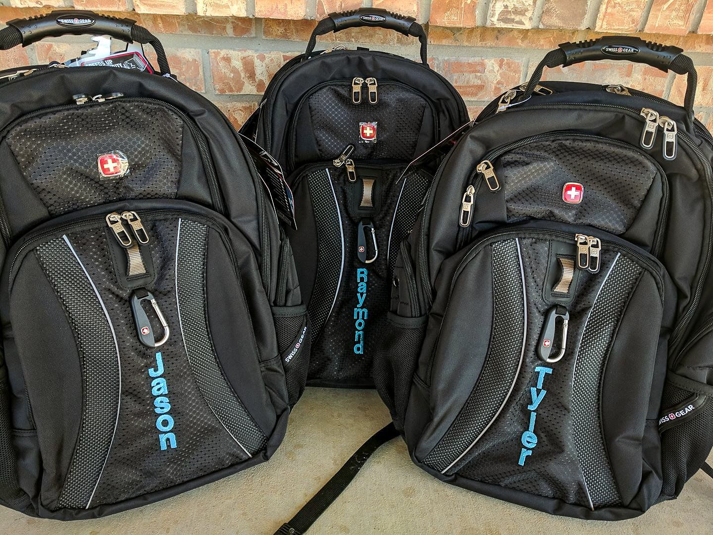 Three black backpacks with embroidered names 