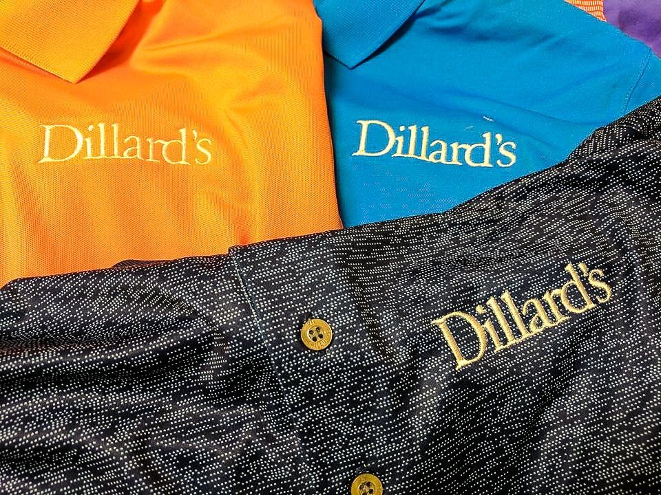 Three polo shirts, orange, blue, and black, with the embroidered 