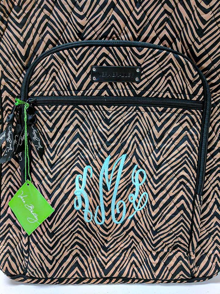 Brown and black chevron patterned backpack with blue monogram, brand tag.