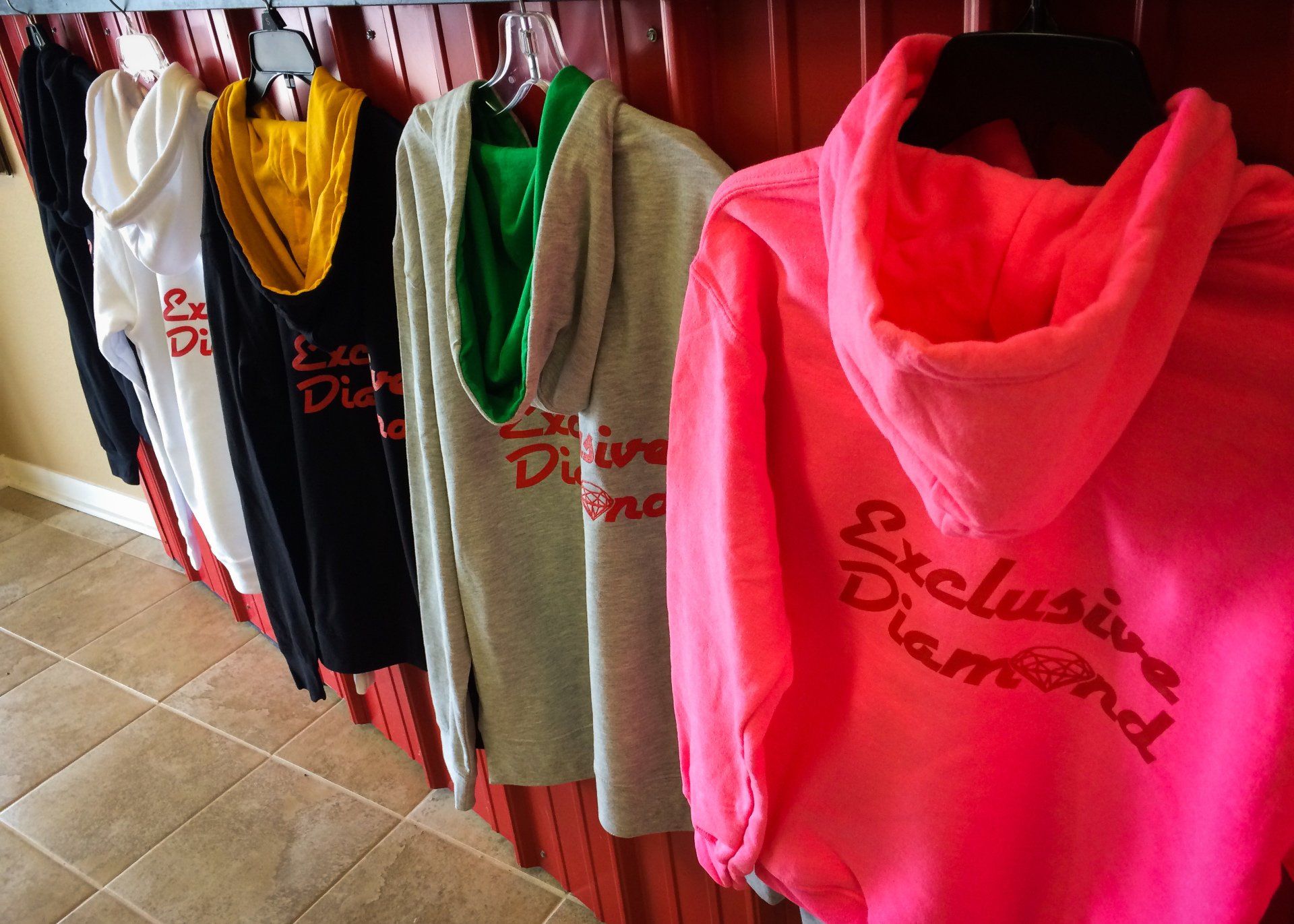 Row of hoodies in various colors, including pink, gray, black, and white, with 