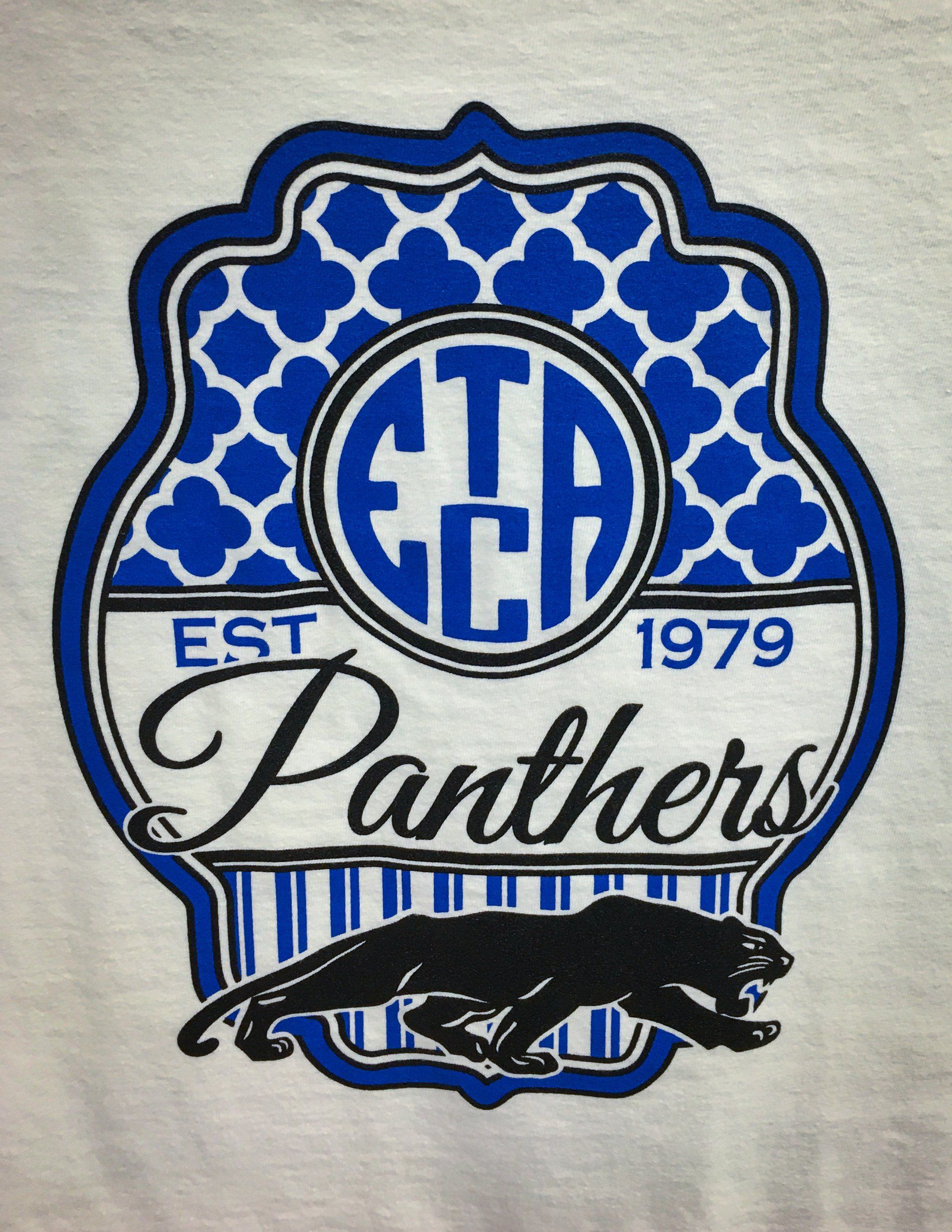 White shirt with blue and white school emblem. 