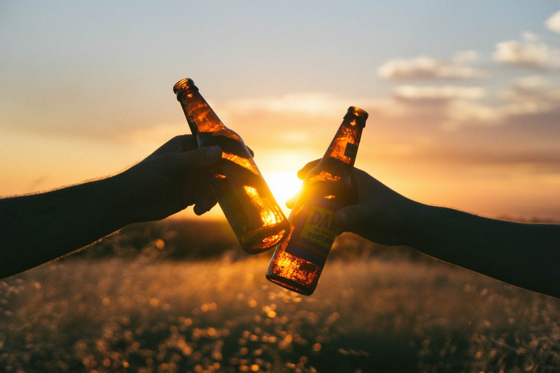 Proosten bierfles ondergaande zon