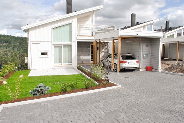 Steinlagt innkjørsel og uteområde foran moderne bolig.