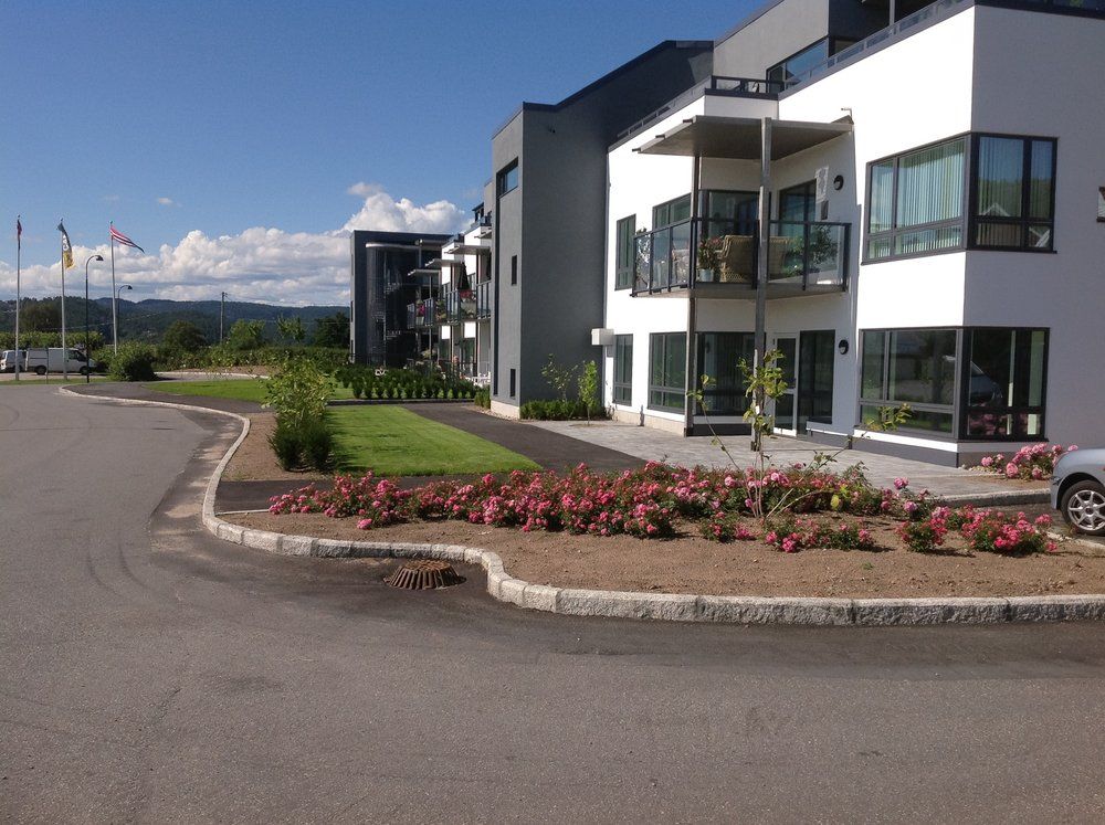 Opparbeidet uteområde med plen og rosebed foran leilighetsbygg.