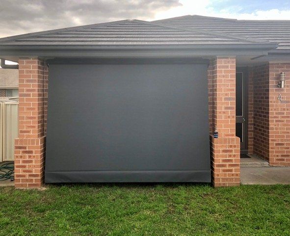 A brick house with a black garage door — Plantation Shutters in Singleton, NSW