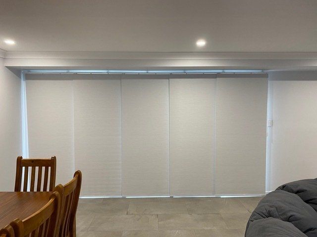 A living room with a table and chairs and a couch — Plantation Shutters in Singleton, NSW