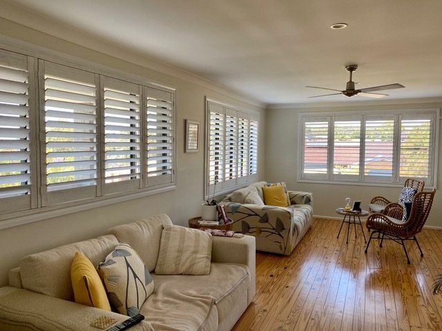 A living room with a couch , chair , table and ceiling fan — Plantation Shutters in Singleton, NSW