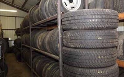 Tires stacked on shelves in a storage room; some tires have wheels.