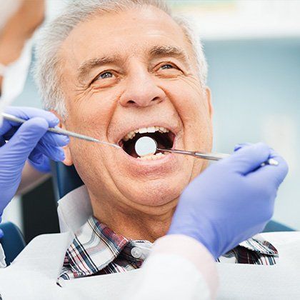 elder man having teeth examined