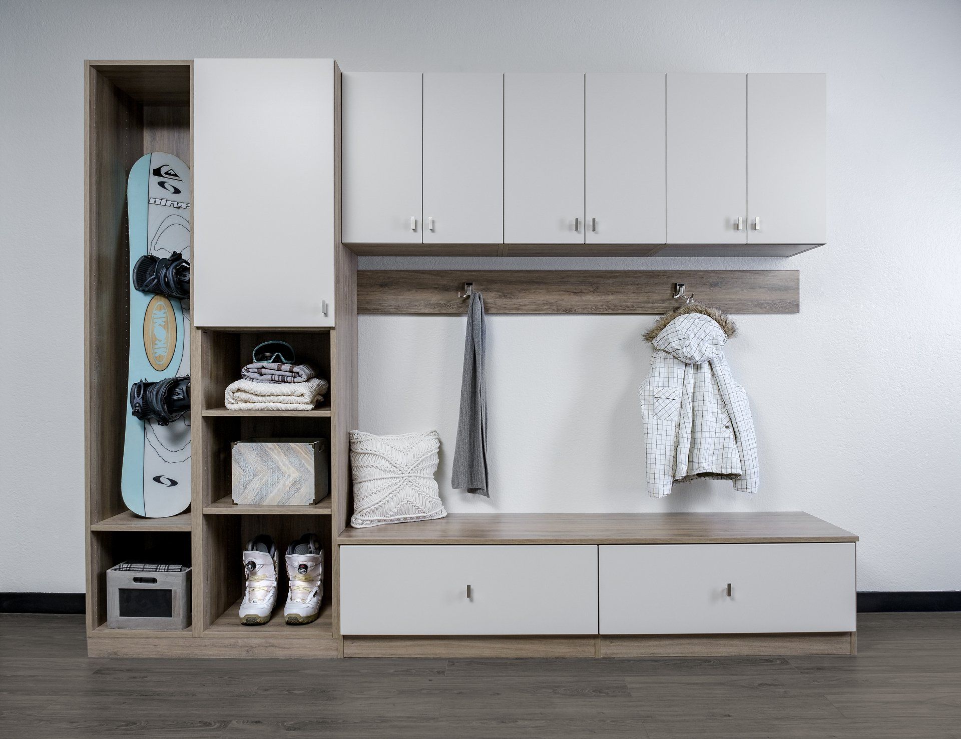a mudroom with a snowboard hanging on the wall and a coat hanging on the wall .