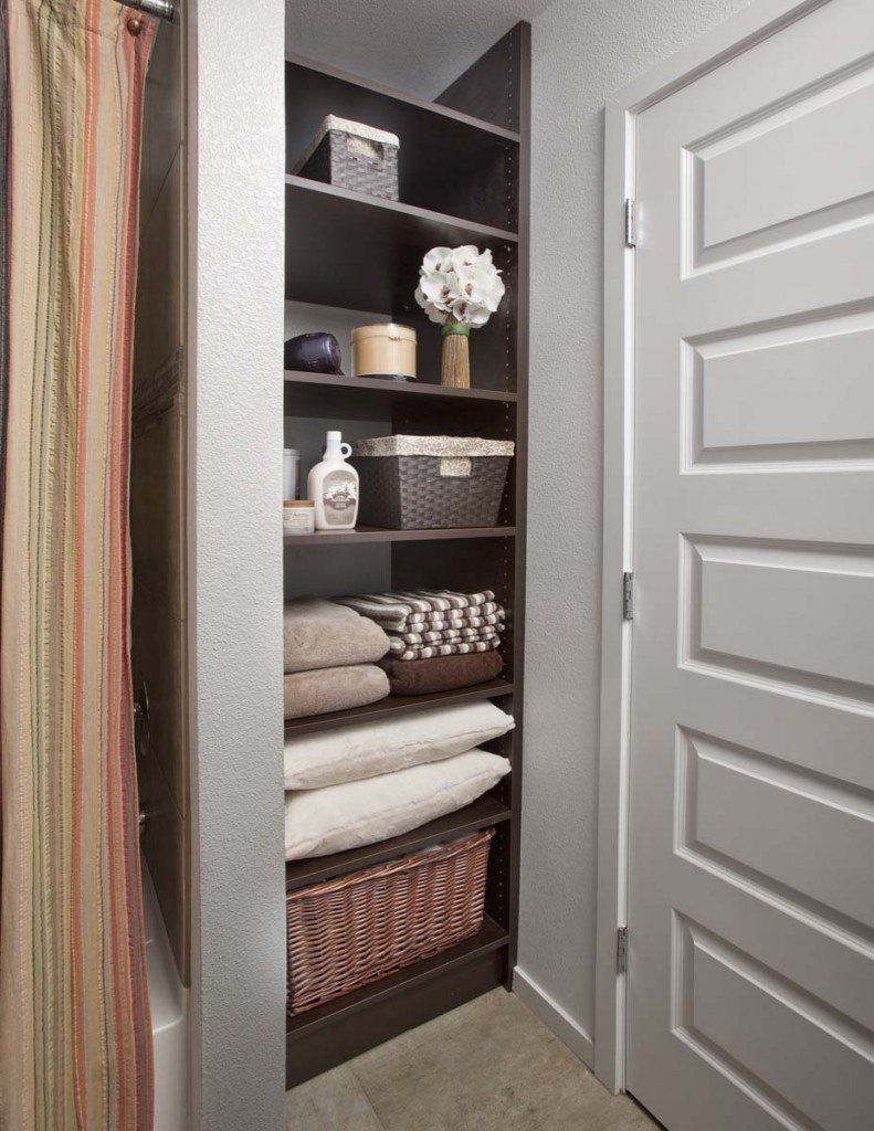 a bathroom with a closet filled with towels and baskets