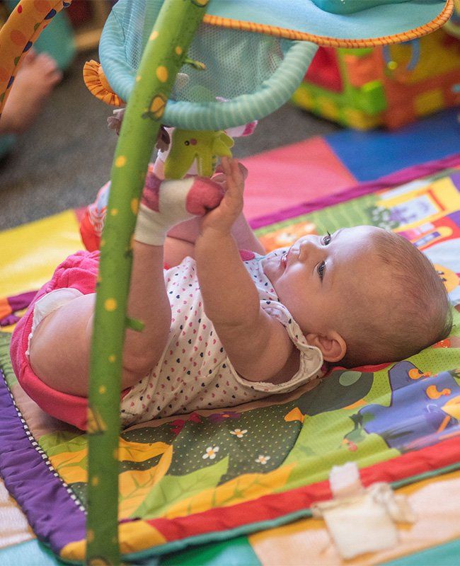Baby Playing with Hanging Toys — Mokena, IL — Triple R Child Care Baby Playing with Hanging Toys — Mokena, IL — Triple R Child Care