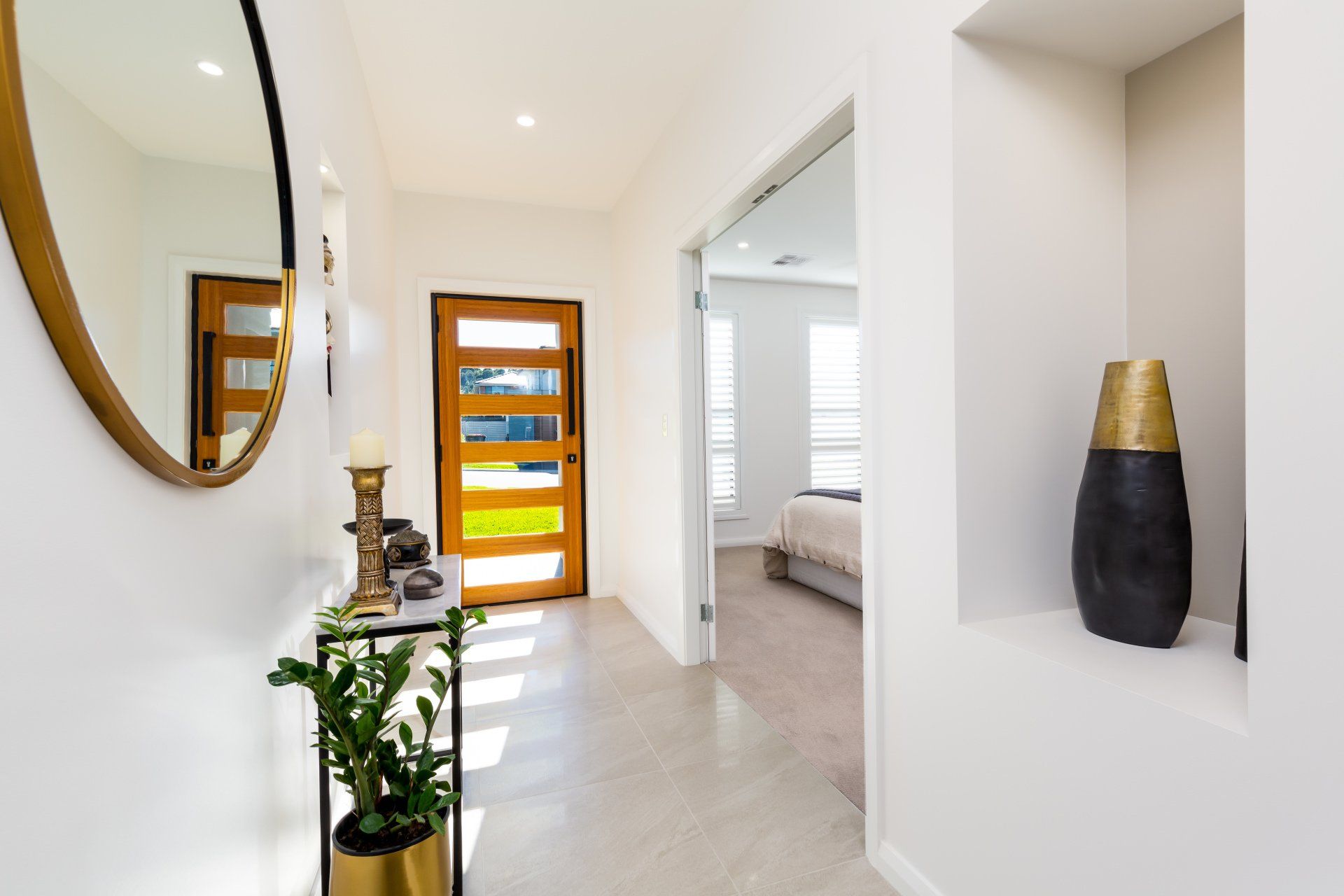 Hallway with a gold-framed mirror, a wooden door, and a decorative vase.
