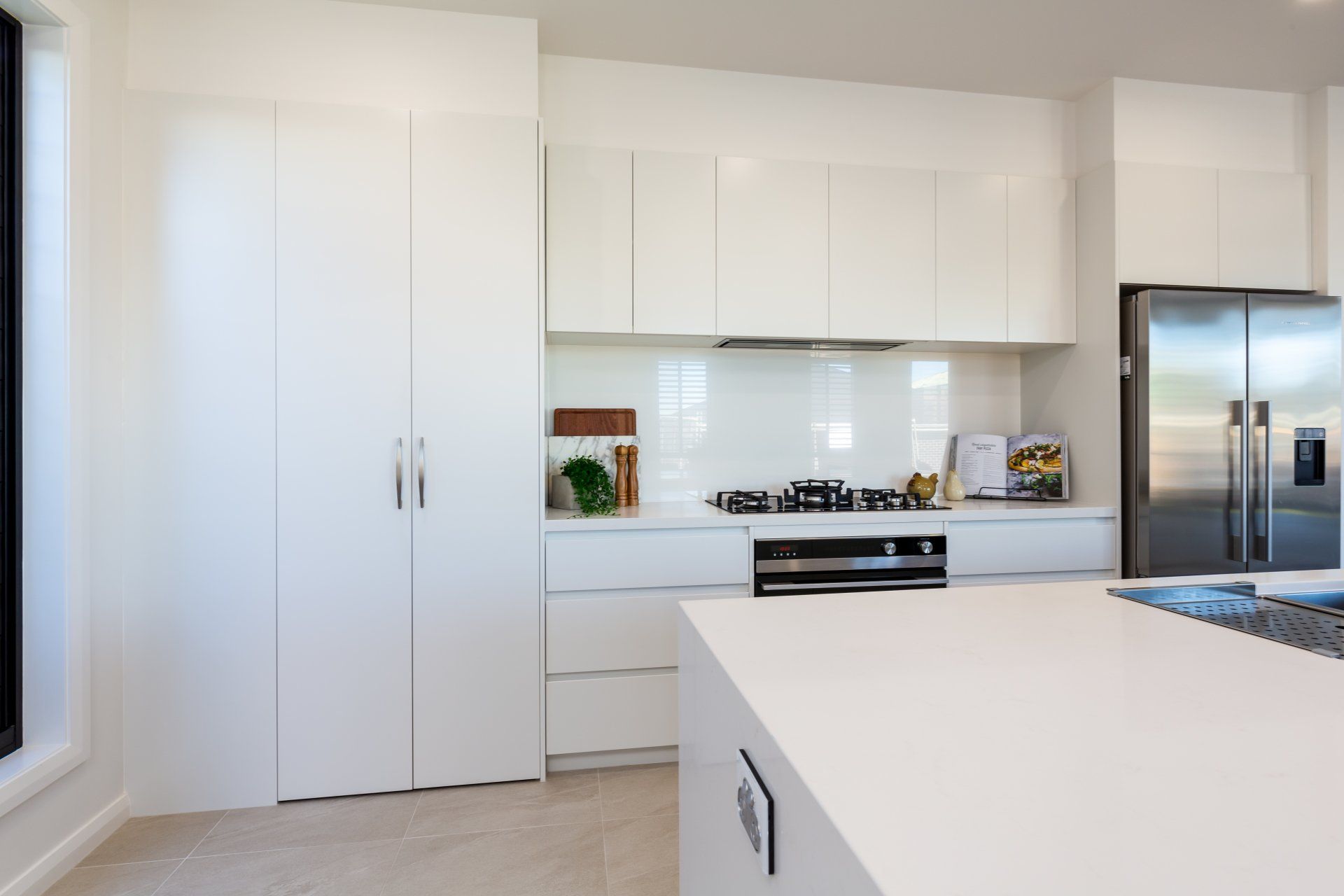 White modern kitchen with large cabinets, stainless steel appliances, and an island.