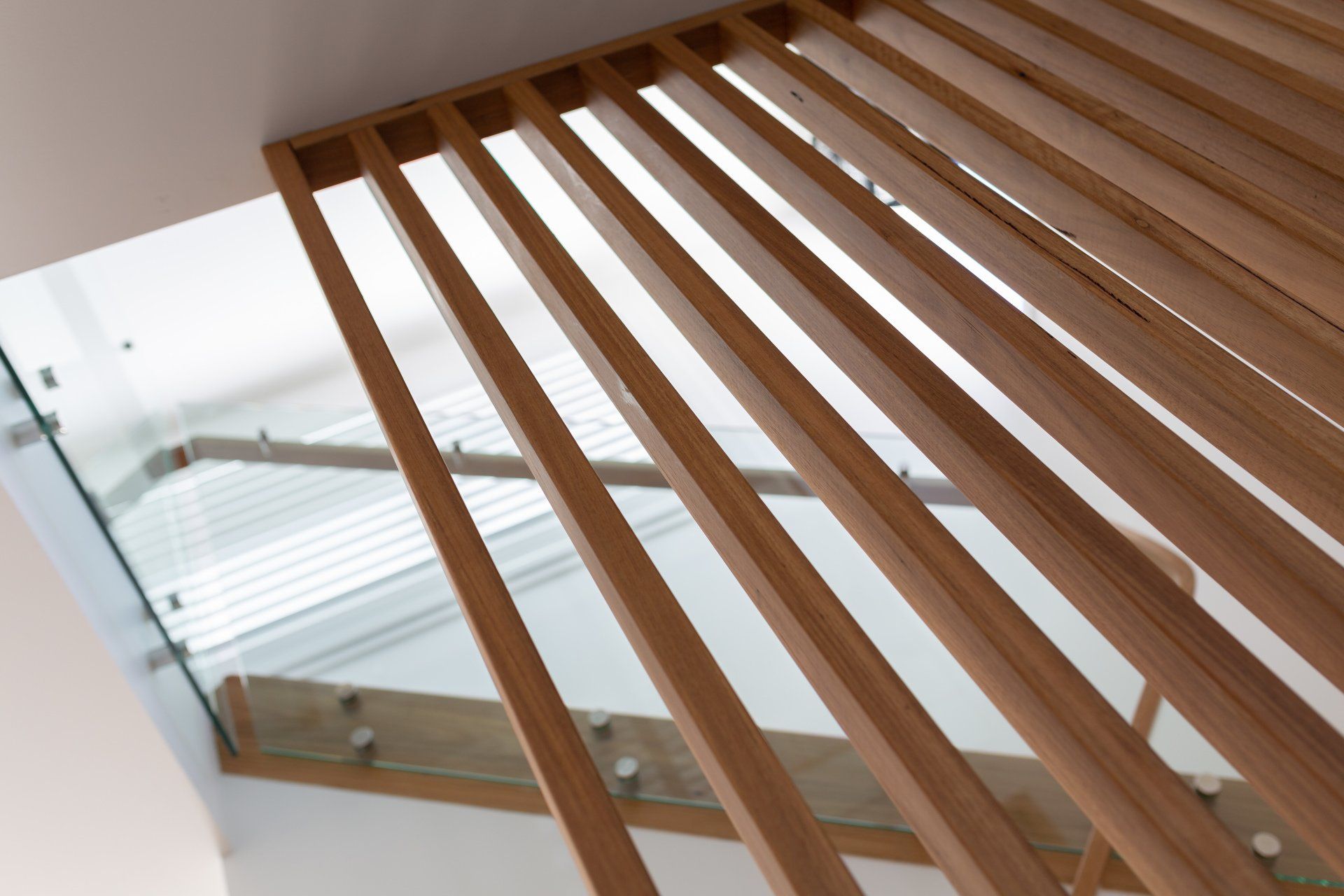 Wooden slat divider beside a modern staircase with glass railing.