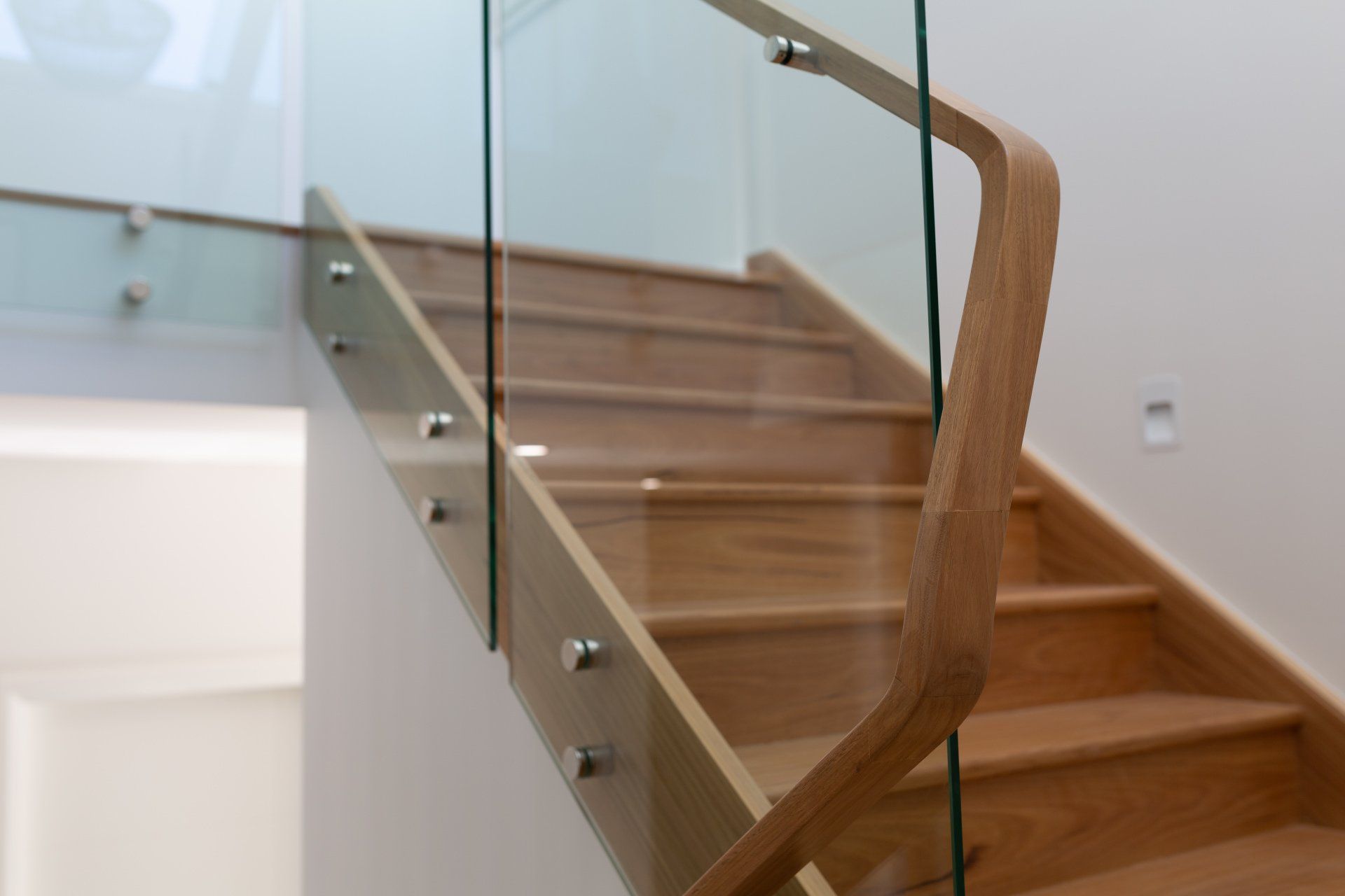 Wooden staircase with glass railing.