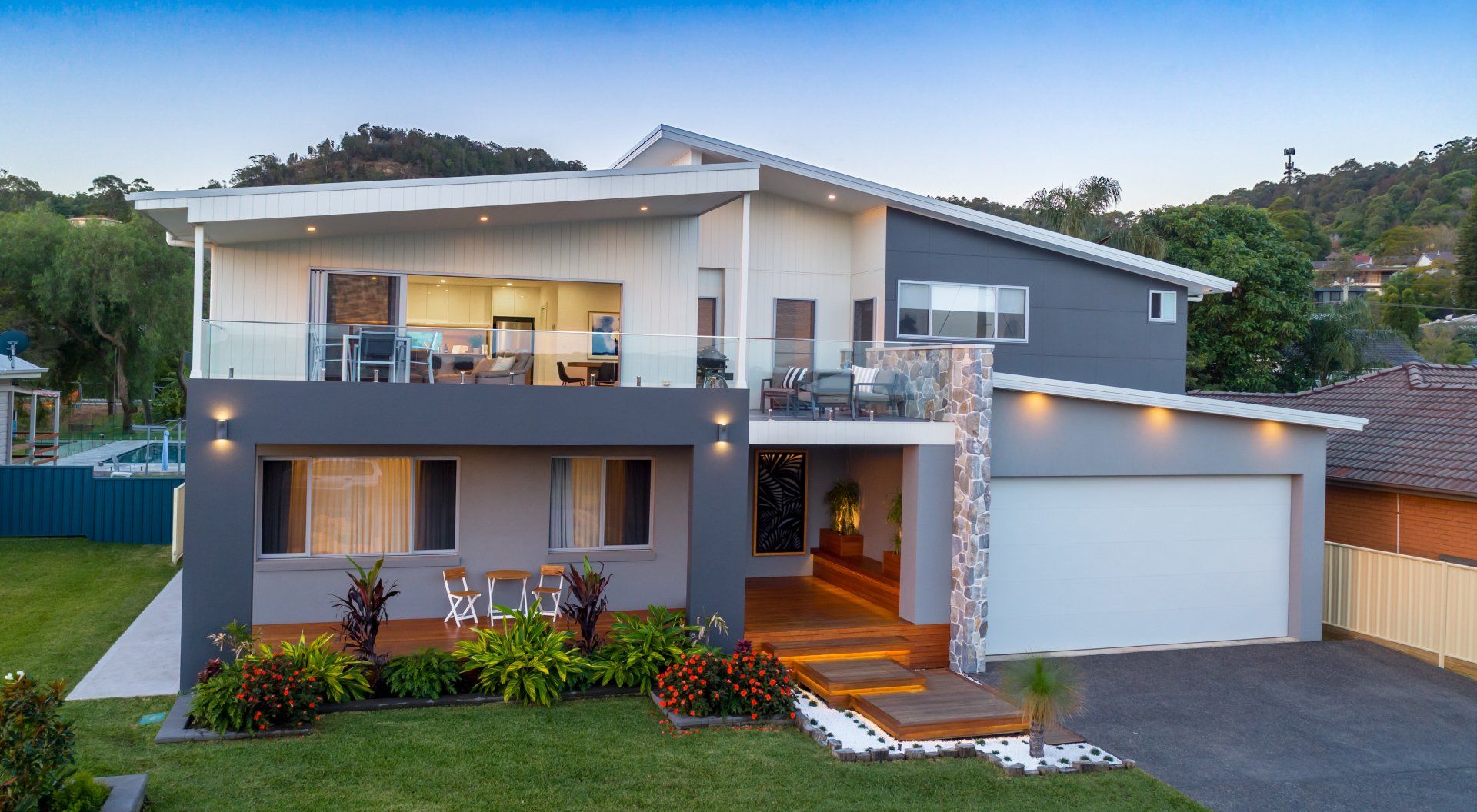 Modern two-story house with gray and white exterior, balcony, and attached garage.